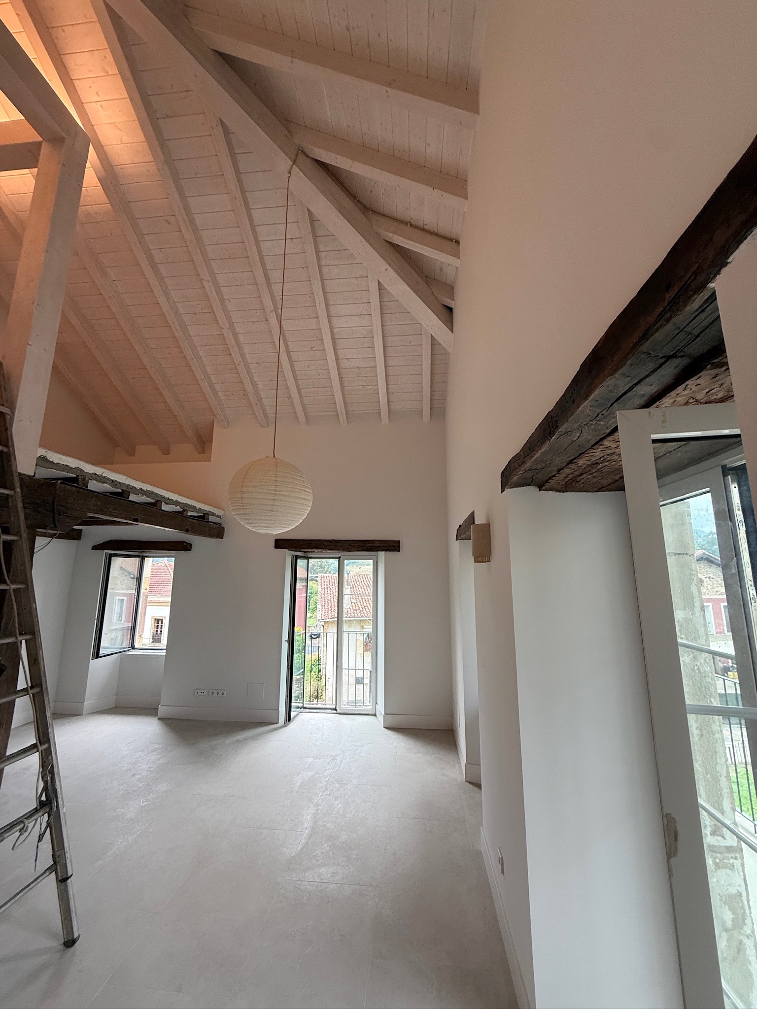 Interior de doble altura con paredes claras y techo de madera blanco